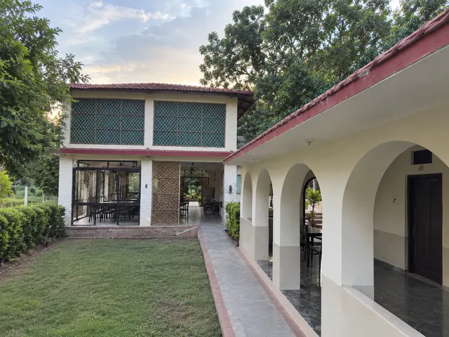 Two-storey resort building with a lattice-windowed upper floor beside a green lawn and an arched veranda at dusk