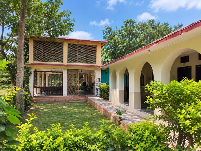Two-storey lattice-windowed building beside an arched veranda and a green lawn with shrubs