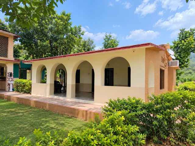 Single-storey pavilion with a row of arches facing a green lawn and trimmed hedges