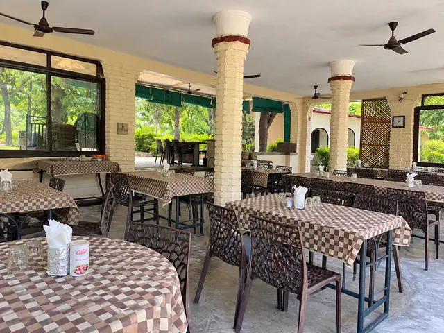 Open-air restaurant patio at Roopam Resort with brick pillars, dining tables and views of the garden