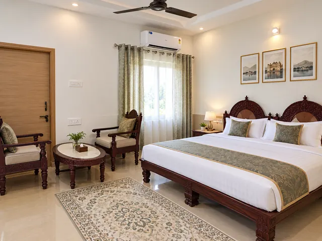 Spacious resort room with a king bed, carved wooden chairs, a round table and a patterned rug